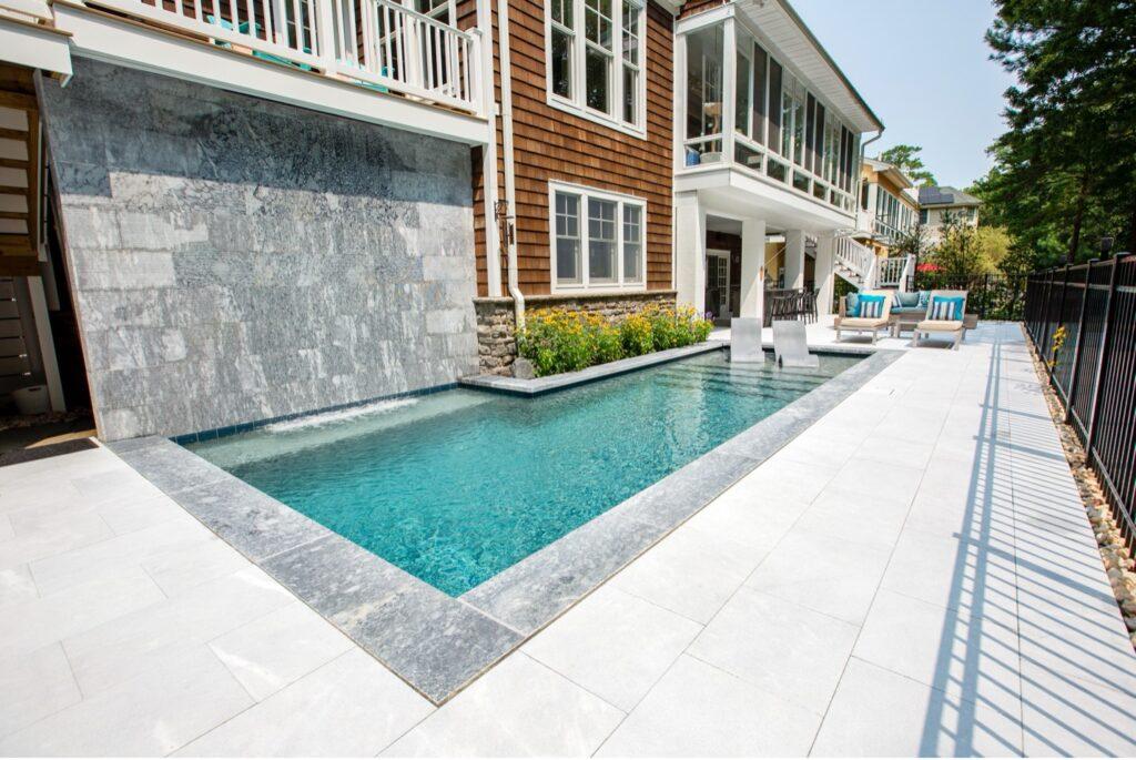 A pool with a waterfall in the back with beautiful pavers chosen at a backyard design meeting